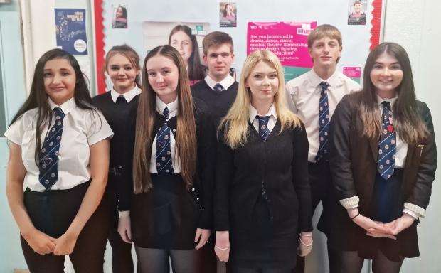 Group of secondary school children standing in school corridor