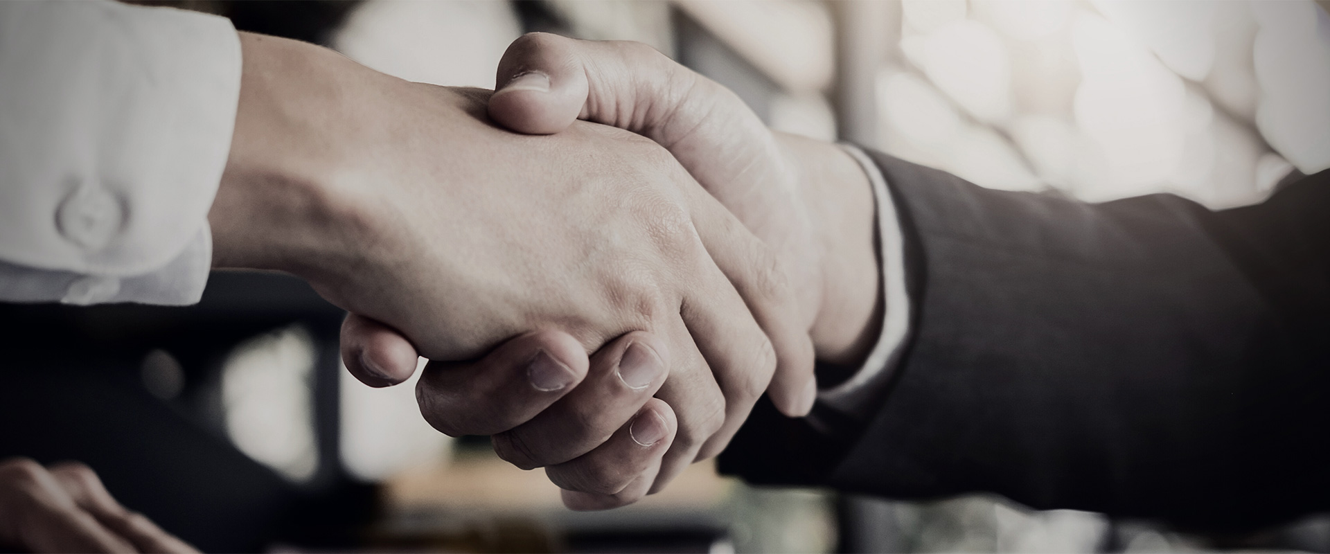 Close up image of two people in corporate clothing shaking hands