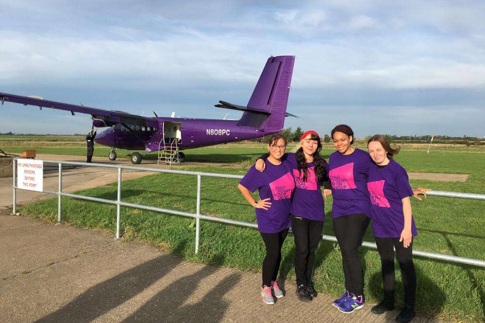 group of skydivers standing in front of a plane